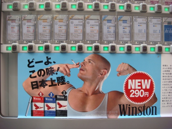 Taken at the end of my street in Tokyo. Dispensing machines for anything and everything are everywhere but the advertising on this one got me every time I walked past it.  Smoke and you'll turn into a muscled westerner?